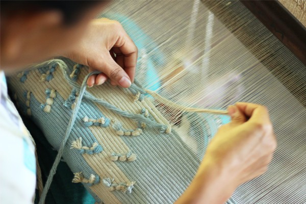 A weaver using a wooden loom
